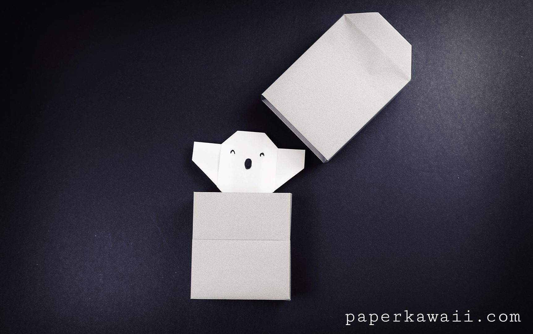 A cute origami ghost coming out of an origami tombstone box!